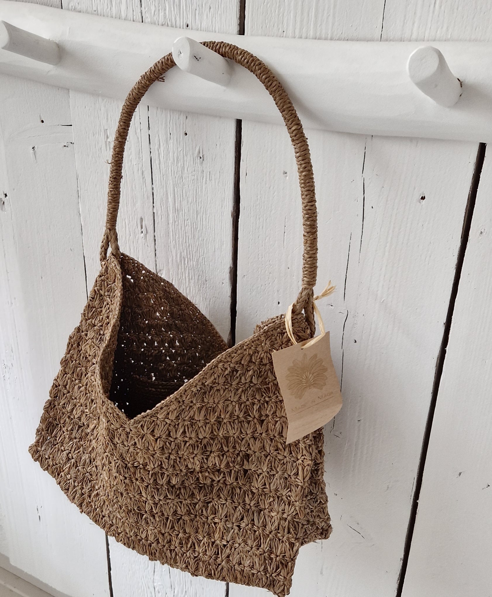 Valiha Bag van Made in Mada aan witte houten haak, handgeweven raffia tas.