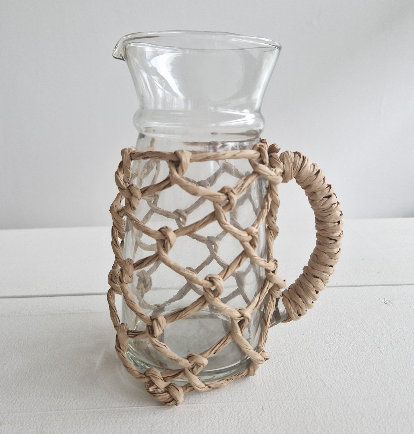 Glass water jug with refined raffia braiding