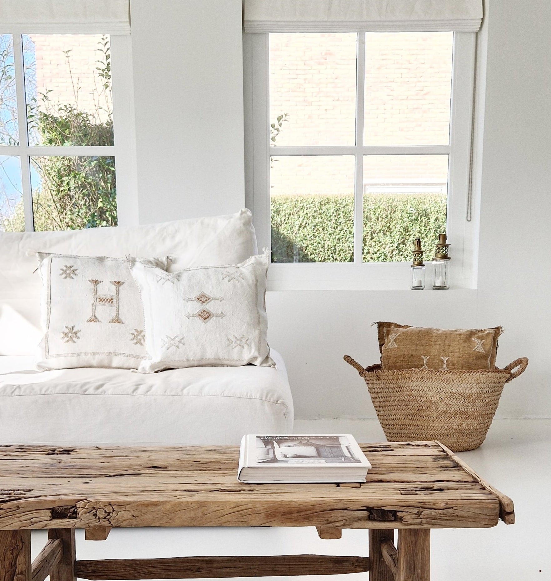 Marokkaanse Sabra Silk kussens in off white en lichtbruin op witte bank met houten salontafel