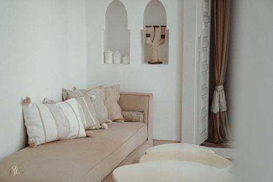 Marokkaanse pompom kussens in off-white en beige gecombineerd met sabra silk kussens op een sofa in een warm en licht interieur