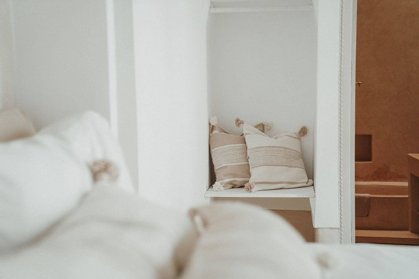Marokkaanse pompom kussens off-white en beige in lichte slaapkamer