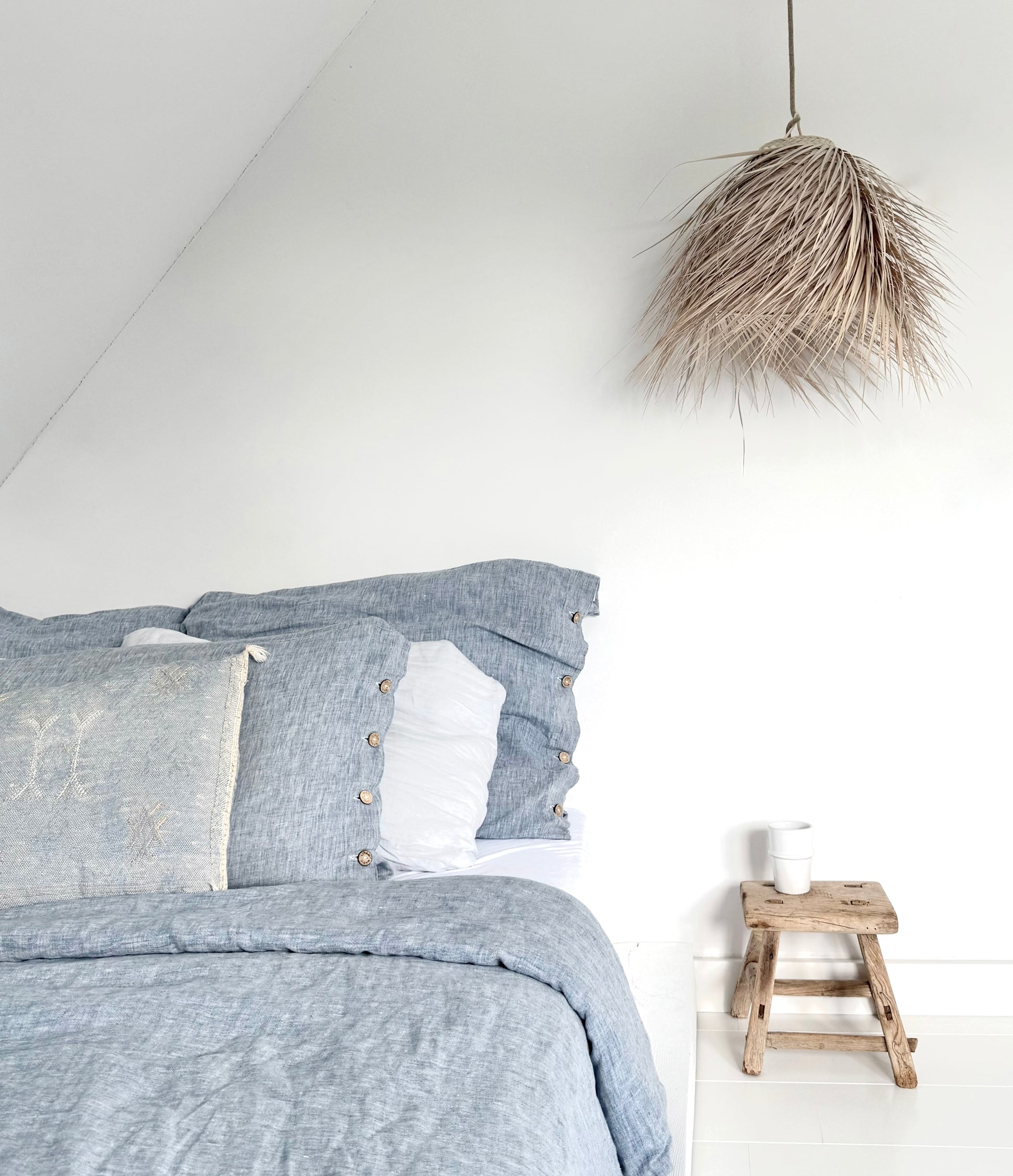 Palmleaf cloche lamp small boven bed met   blauw linnen beddengoed