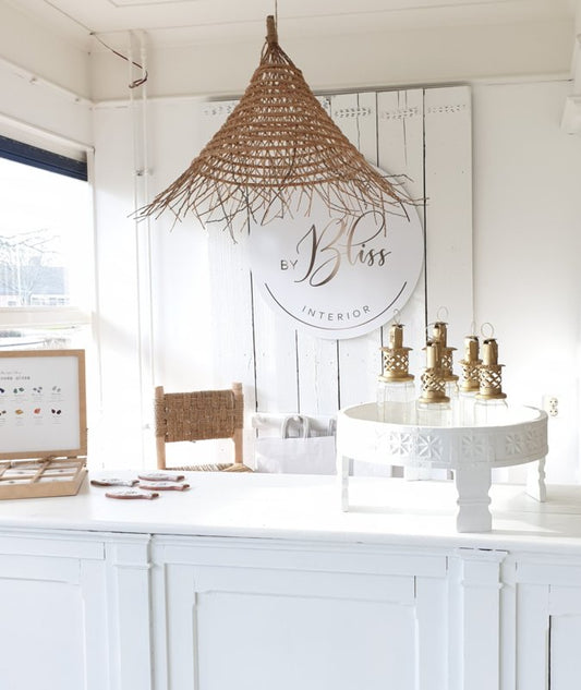 Wit interieur met witte chakki tafel met goudkleurige marokkaanse jampot lantaarns. En een dadel hanglamp daarboven.